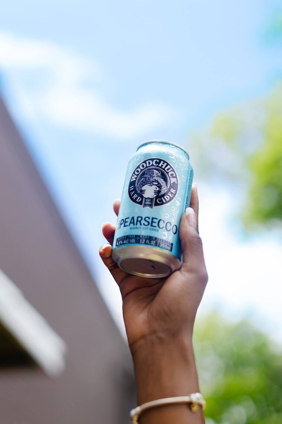 Hand holding a can of Woodchuck Pearsecco in the air